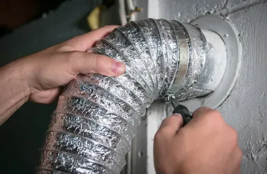 Hands tightening a clamp on a foil flex duct collar during duct sealing