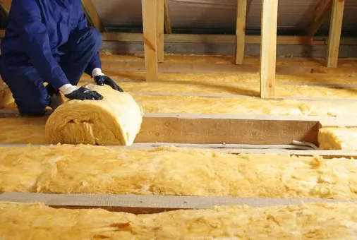 Fiberglass batt insulation being rolled out across attic joists in Pasadena