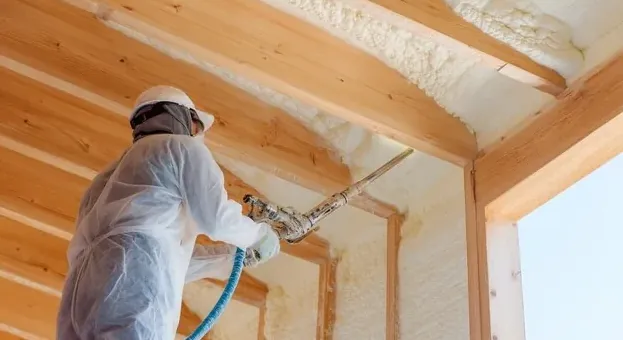 Installer spraying foam insulation onto the underside of a roof deck